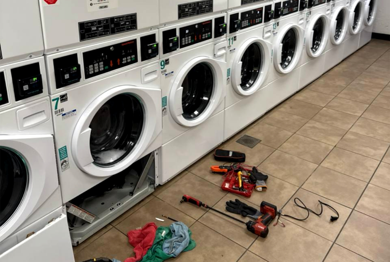 Commercial washer repaired in a laundromat after accessing the lower section to fix a leak in Katy, TX.